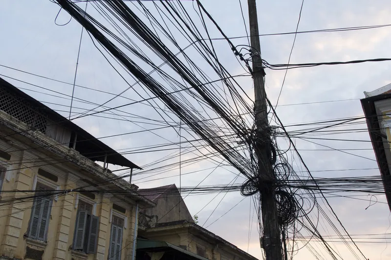 Tangle of power and data cables on a pole above colonial houses in Battambang. Cables added piecemeal like this are the norm in Cambodian towns.