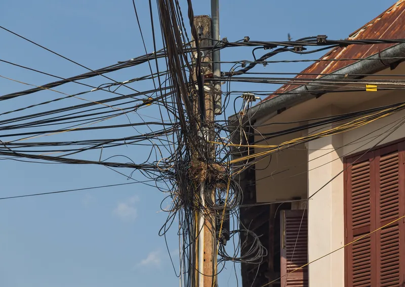 Ungeordnetes Kabelbündel an einem Strommast in einer Straße von Kampot (typisch für die gewachsene Strom- und Datennetz-Infrastruktur kambodschanischer Städte)
