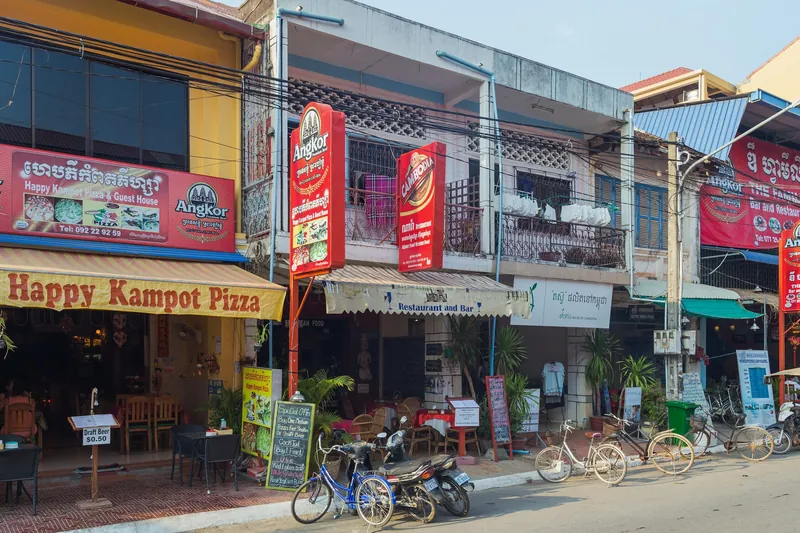 Shops and restaurants on Old Market Street in Kampot with parked bicycles and motorbikes