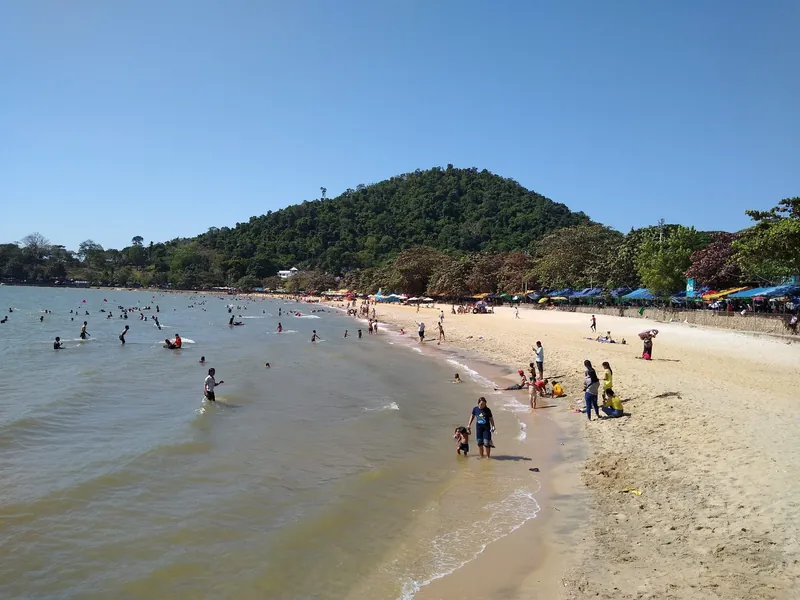 Kep Beach, der Stadtstrand von Kep, mit Badenden und den bewaldeten Hügeln des Kep-Nationalparks