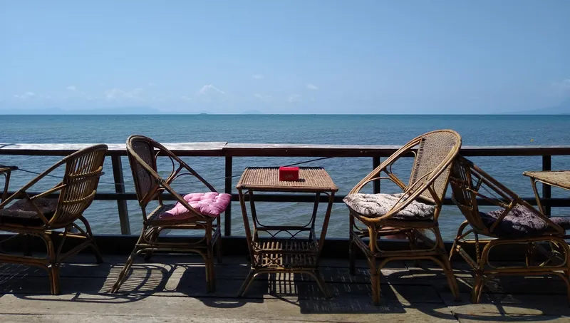 Rattan furniture on a coastal restaurant terrace in Kep overlooking the Gulf of Thailand