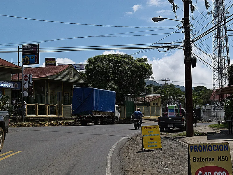 Main road (Ruta 3) through Atenas with shops, trucks and overhead power lines