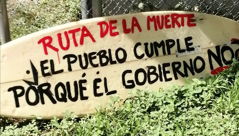 Protestschild auf einem Surfbrett gegen die unbefestigte Ruta 160 in Nosara, 15. November 2019 (Aufschrift: Ruta de la Muerte - El pueblo cumple porque el gobierno no)