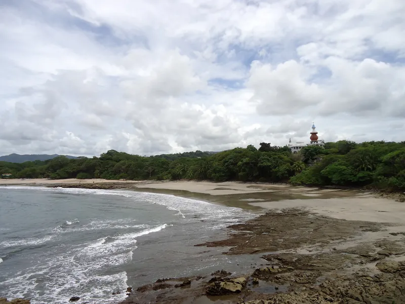 Playa Nosara mit Felsplatten bei Ebbe und bewaldeter Küste