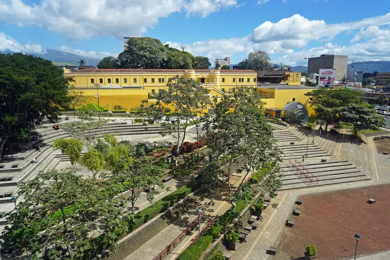 Begrünte Plaza de la Democracia in San José mit dem Museo Nacional im Hintergrund