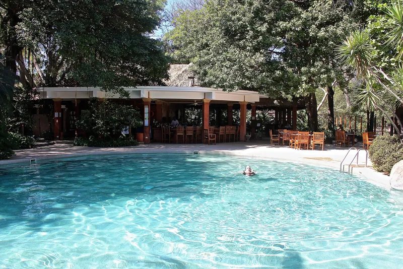 Pool, Restaurant und Bar einer Hotelanlage in Tamarindo unter Bäumen