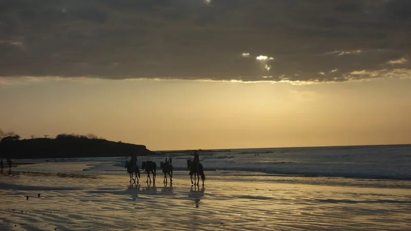 Reitergruppe bei Ebbe am Strand von Tamarindo im Sonnenuntergang