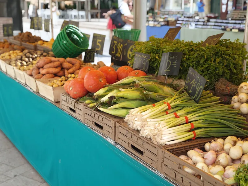 Gemüsestand mit Kürbissen, Frühlingszwiebeln und Preisschildern in Euro auf einem Straßenmarkt in Aix-en-Provence