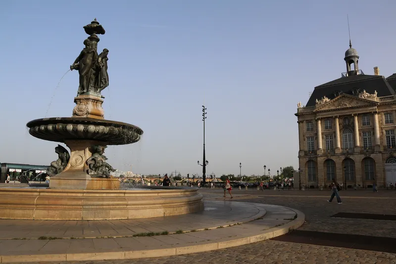 Place de la Bourse in Bordeaux mit dem Brunnen der Drei Grazien und der Börse von 1749, im Hintergrund die Pont de Pierre