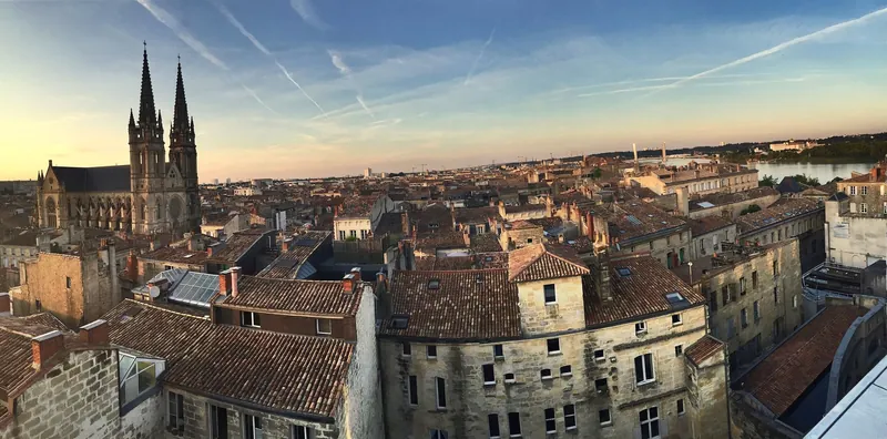 Blick über die Ziegeldächer von Bordeaux zur Garonne bei Sonnenuntergang, links die Kirche Saint-Louis-des-Chartrons