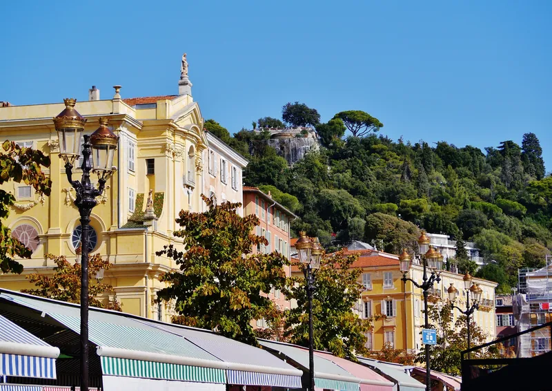 Barockfassaden am Cours Saleya vor dem bewaldeten Schlossberg Colline du Château in Nizza