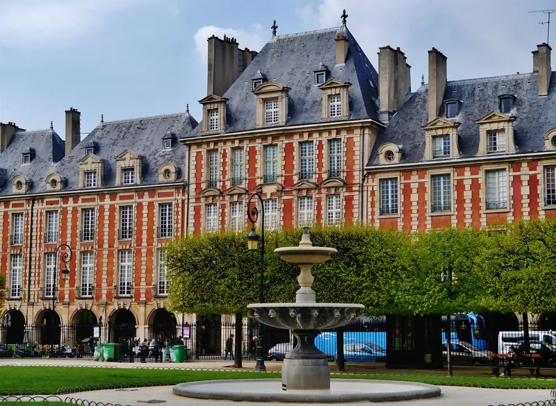 Backsteinfassaden und Brunnen der Place des Vosges von 1612 im Marais-Viertel von Paris