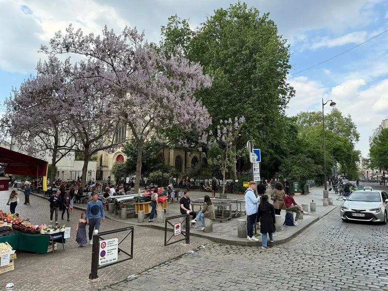 Marktstände der Rue Mouffetard an der Kirche Saint-Médard in Paris unter blühenden Blauglockenbäumen