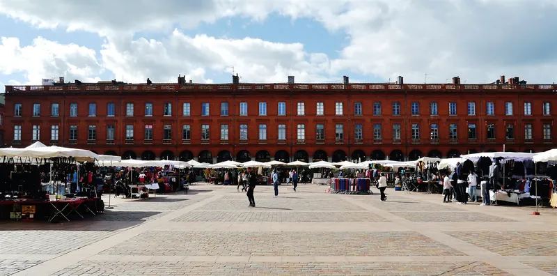 Backsteinarkaden an der Place du Capitole in Toulouse mit Marktständen