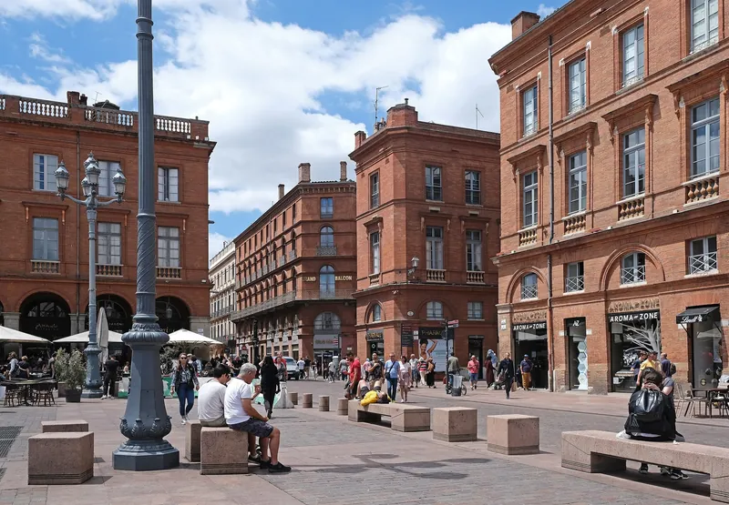 Square with brick houses and café terraces near the Capitole in central Toulouse