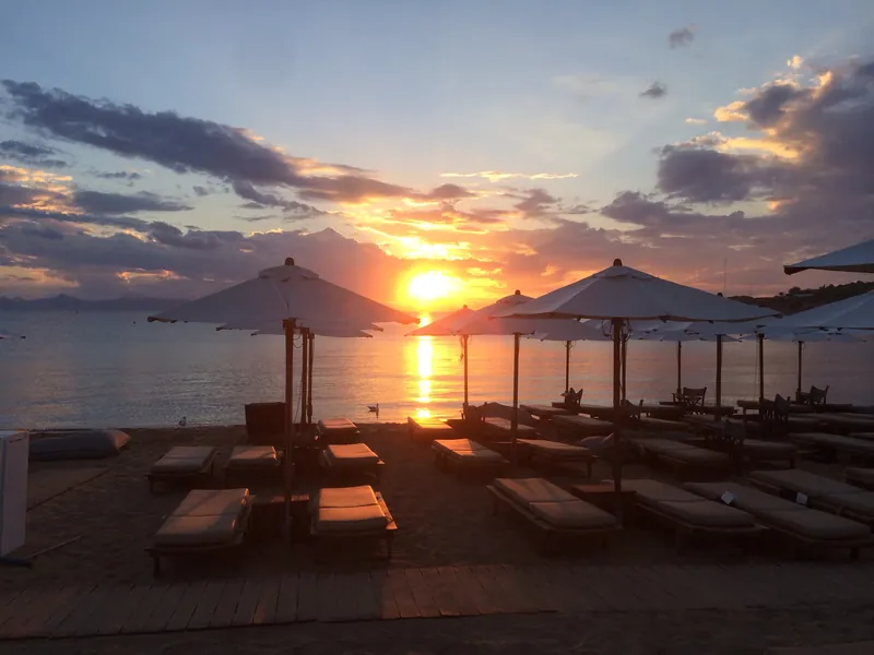 Liegen und Sonnenschirme am Astir Beach in Vouliagmeni an der Athener Riviera bei Sonnenuntergang