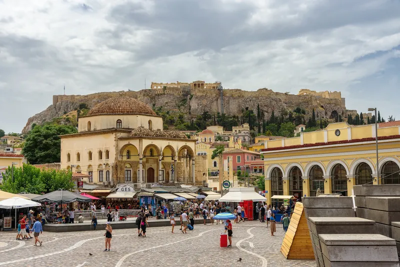 Monastiraki Square in Athens with market stalls, cafés and passers-by, the Acropolis rock behind