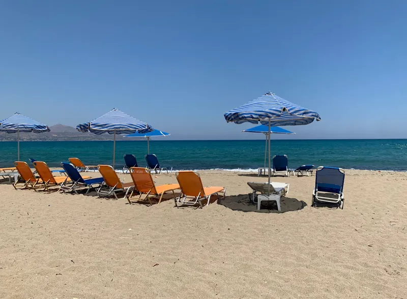 Liegen und Sonnenschirme am Strand von Kalyves bei Chania auf Kreta