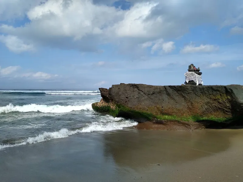 Felsen mit Hindu-Altar in der Brandung am Strand von Canggu