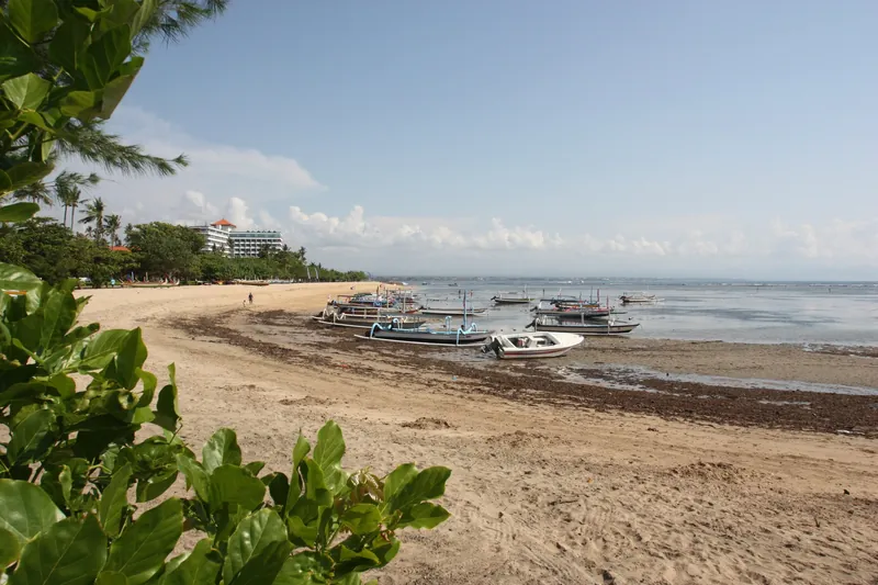 Sandstrand von Sanur mit Fischerbooten und Hotelanlage im Hintergrund