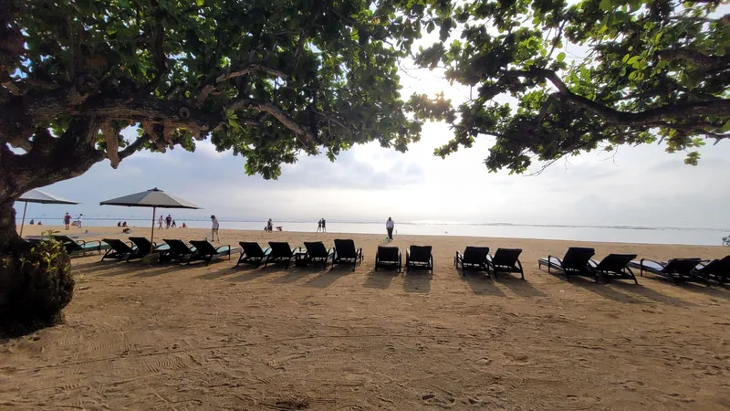 Liegestühle und Sonnenschirme am Strand von Sanur am Morgen