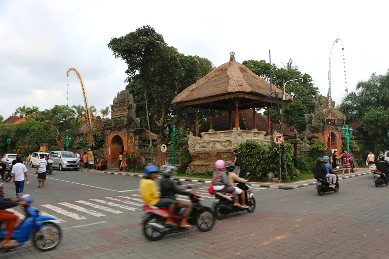 Street outside Puri Saren (Ubud Palace) with scooters and penjor bamboo poles, Ubud