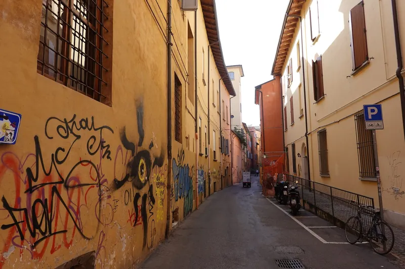 Wohnstraße mit abgestellten Fahrrädern und Graffiti in der Altstadt von Bologna