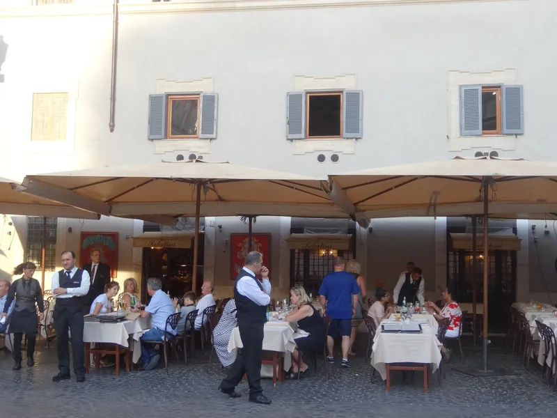 Restaurantterrasse mit Kellnern und Gästen an der Piazza di Santa Maria in Trastevere in Rom