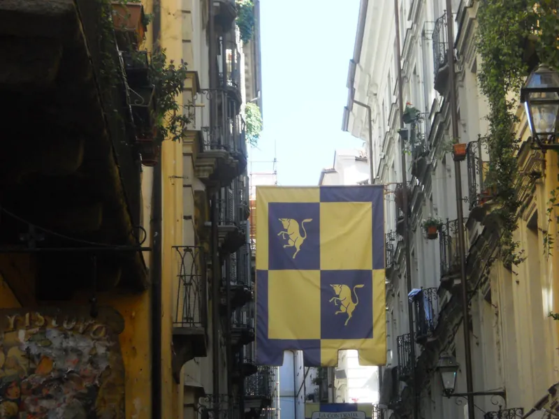 Lane in Turin's Quadrilatero Romano nightlife district, hung with city coat-of-arms flags