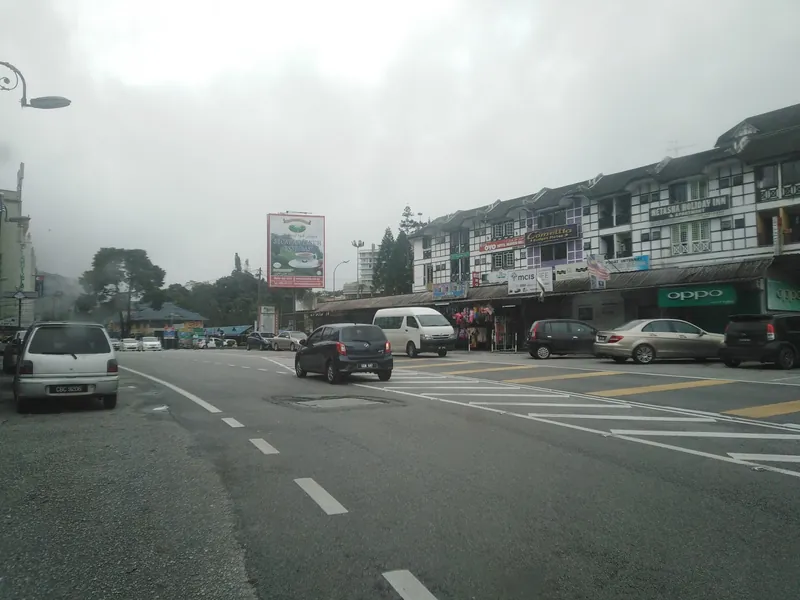 Main street of Tanah Rata with a row of shops and mist over the hills, Cameron Highlands