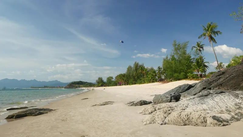 Sandstrand Pantai Cenang mit Felsen und Kasuarinen an der Westküste von Langkawi