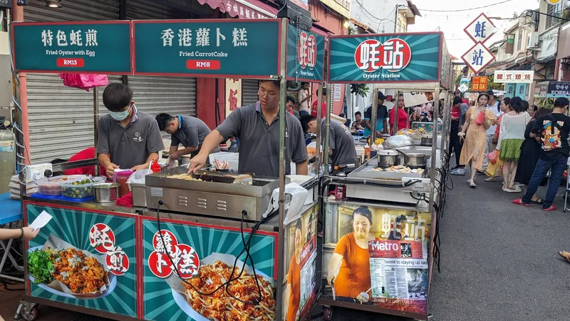 Garküchenstand für Austernomelett und Rettichkuchen mit Preisen in Ringgit am Jonker-Street-Nachtmarkt in Melaka