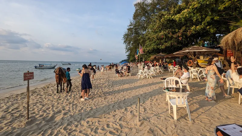 Strand von Batu Ferringhi an der Nordküste von Penang mit Strandrestaurants am späten Nachmittag