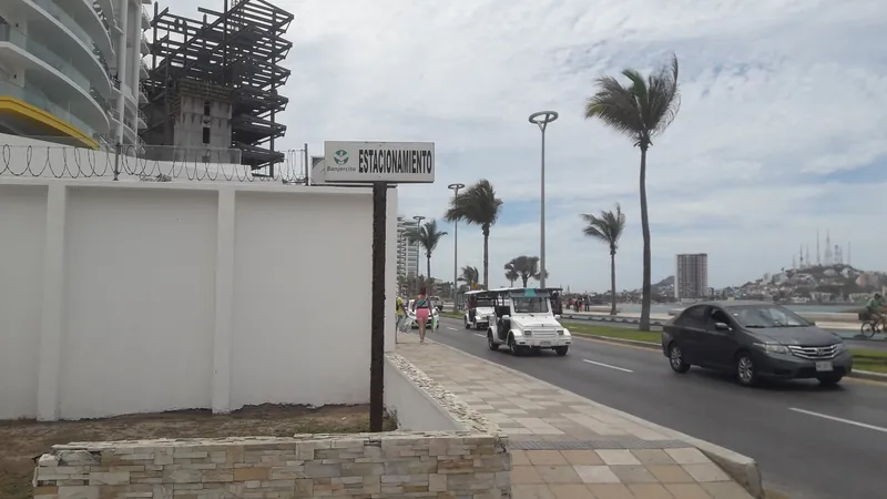 Pulmonía und Autos auf der Avenida del Mar in Mazatlán, im Hintergrund ein Hochhausrohbau