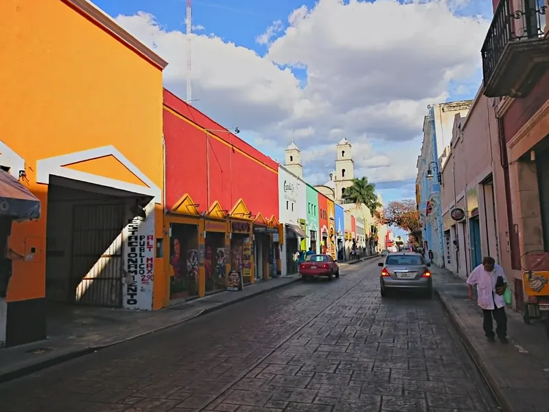Calle 59 im historischen Zentrum von Mérida mit bunten Fassaden und den Türmen der Iglesia de Jesús