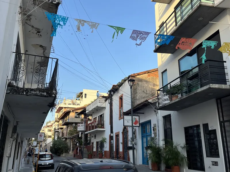 Altstadtgasse im Zentrum von Puerto Vallarta mit Papel-picado-Girlanden, Balkonen und parkenden Autos