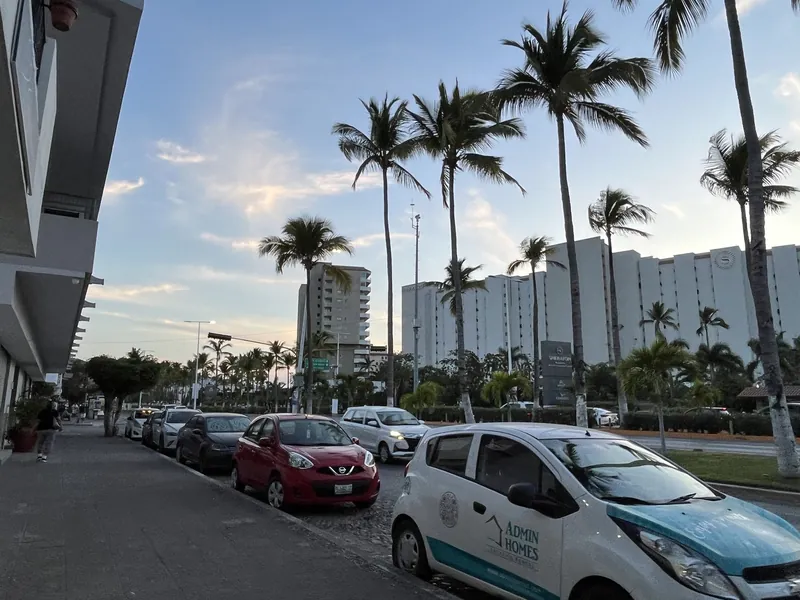 Straße in der Hotelzone von Puerto Vallarta mit parkenden Autos, Palmen und Hotelbauten