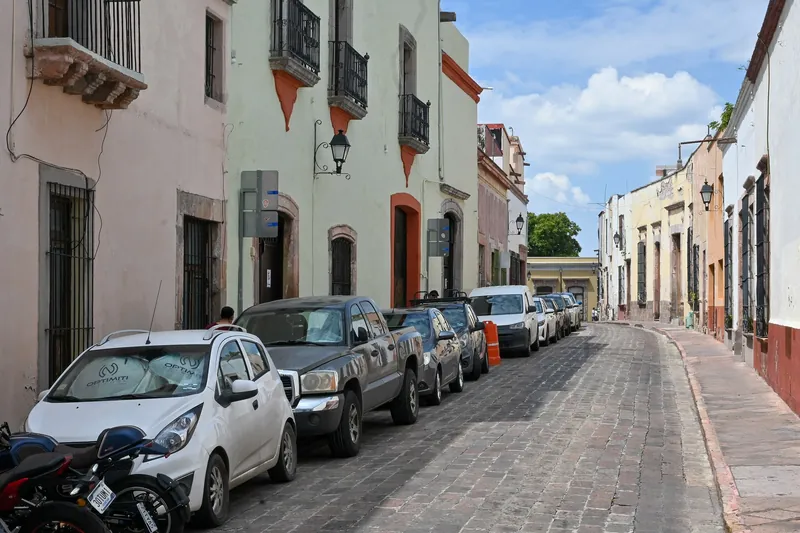 Cobbled old-town street in Querétaro with cars parked on both sides