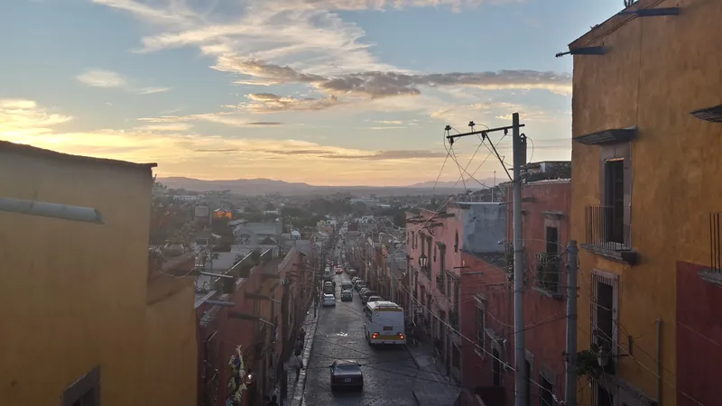 Blick über eine abschüssige Ausfallstraße von San Miguel de Allende mit Bussen und Autos bei Sonnenuntergang