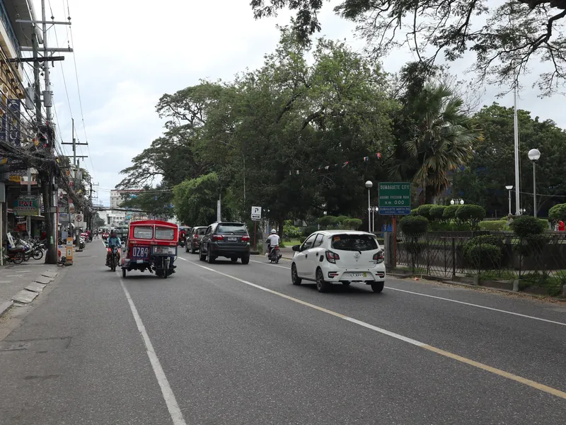 Tricycle und Autos auf der Dumaguete North Road am Kilometerpunkt 0 vor dem Capitol, Dumaguete City
