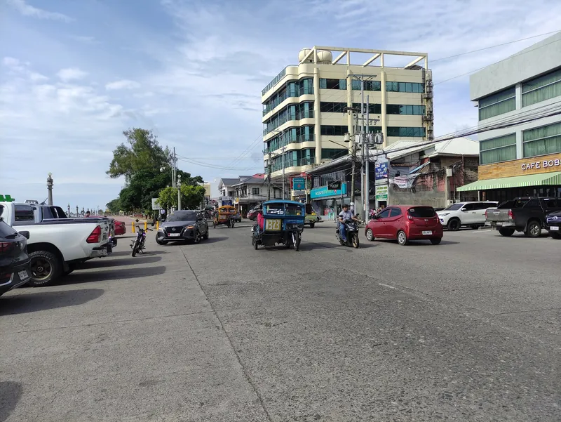Tricycles, Motorräder und Autos auf einer Hauptstraße nahe der Uferpromenade in Dumaguete City
