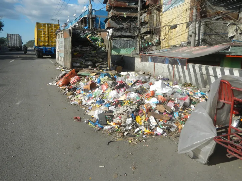 Überquellender Müllhaufen neben einem Sammelcontainer an der Marcos Road (R-10) beim Estero de Vitas in Tondo, Manila