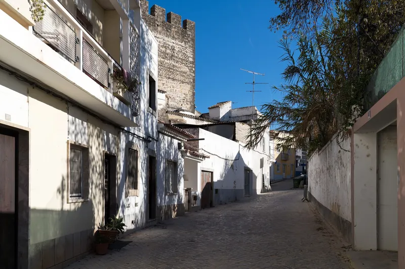 Cobbled Rua das Portas do Postigo below the castle wall in Tavira's old town, Algarve