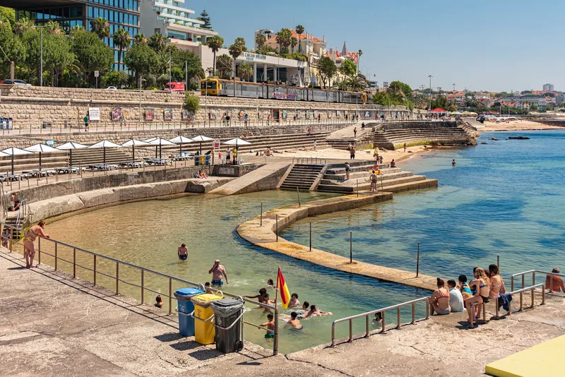 Piscina Oceânica Alberto Romano seawater pool in Cascais, with a Linha de Cascais train above