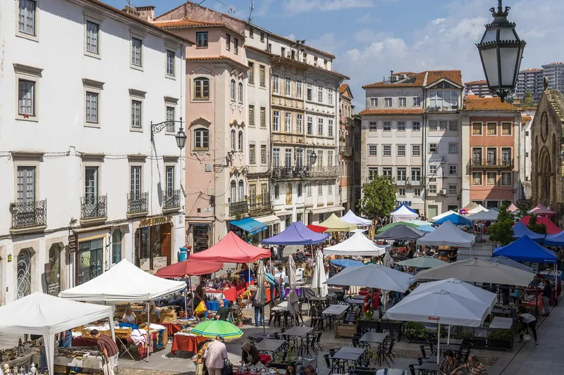 Flohmarkt mit Pavillons und Cafétischen auf der Praça do Comércio in Coimbra
