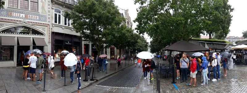 Touristen warten im Regen in der Warteschlange vor der Buchhandlung Livraria Lello in Porto