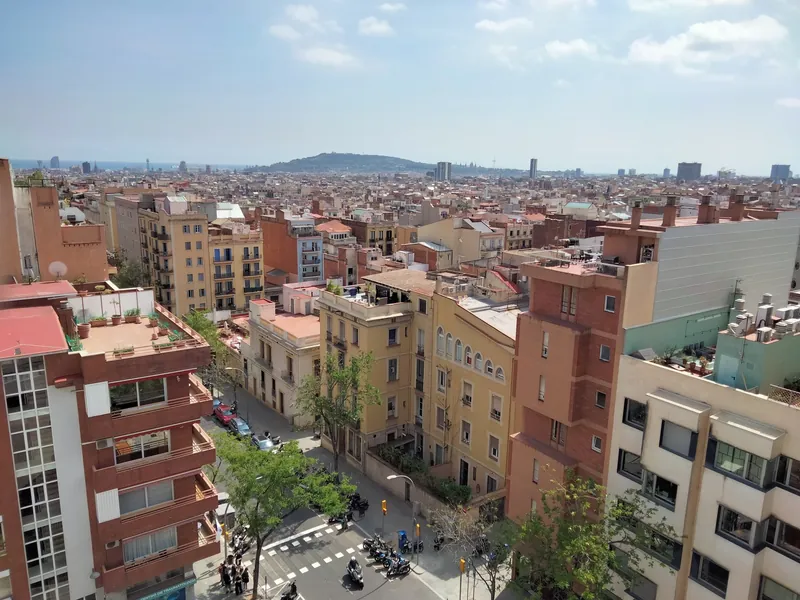 Wohnhäuser an der Carrer d'Escorial im Stadtteil Gràcia in Barcelona, im Hintergrund der Hausberg Montjuïc