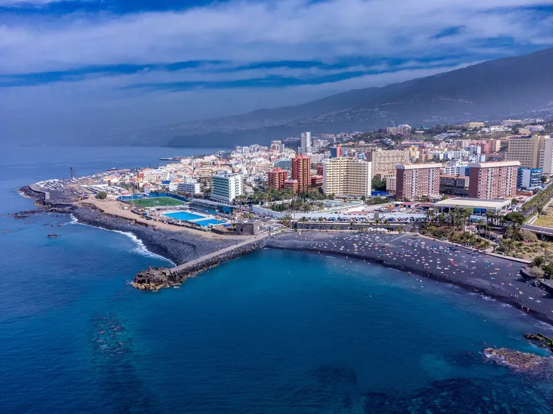 Luftbild von Puerto de la Cruz auf Teneriffa mit der Playa Jardín und den Hotelhochhäusern am Hang