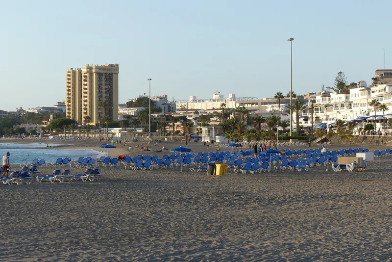 Strand von Los Cristianos im Süden Teneriffas mit Liegenreihen am Abend