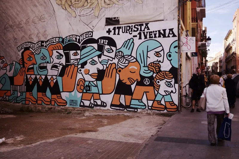 Wandbild +1 Turista -1 Veïna (ein Tourist mehr - eine Anwohnerin weniger) von Elías Taño an der Carrer de Quart in Valencia (Protest gegen Ferienwohnungen und steigende Mieten in der Altstadt)